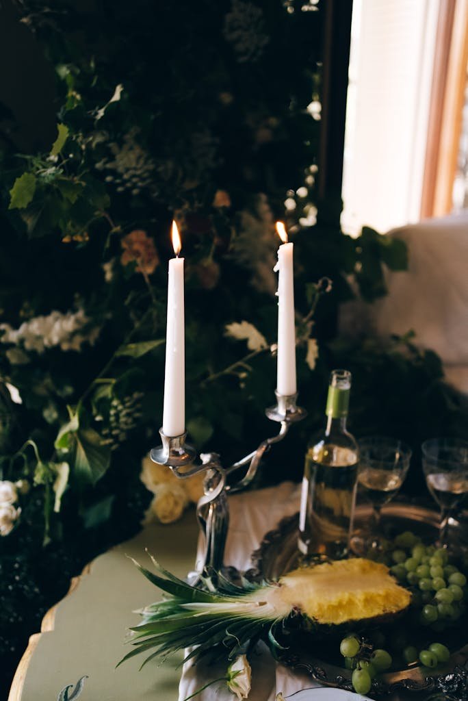 A sophisticated candlelit dining setting with wine, grapes, and floral decor.
