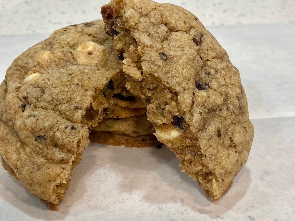 A cookies and cream cookie broken in half showing Oreo pieces and a soft, chewy center. 